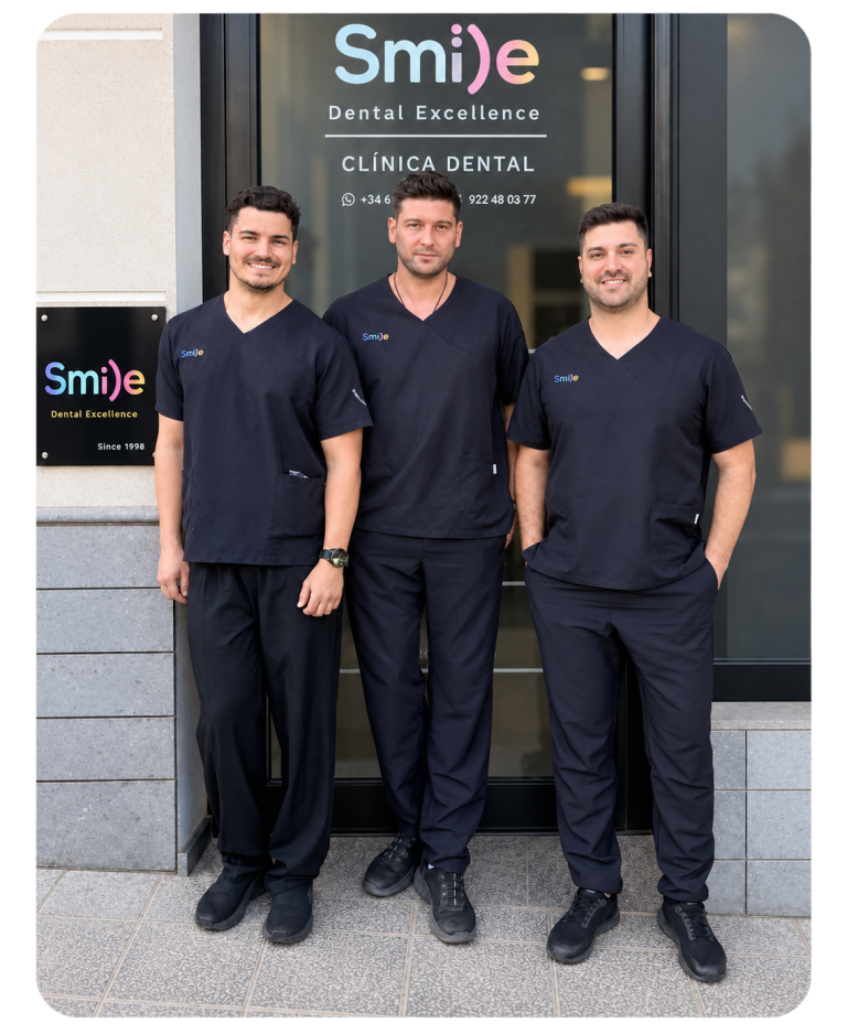 Equipo clínica dental Smile Dental Excellence: tres profesionales con uniforme azul marino frente a la entrada.